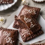 Homemade chocolate fudge pop tarts with glossy chocolate glaze, white sprinkles, and thick fudge filling