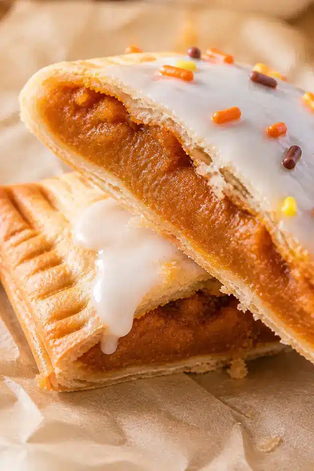 Close-up homemade pumpkin pie pop tarts showing flaky crust, thick pumpkin filling, maple glaze, and sprinkles