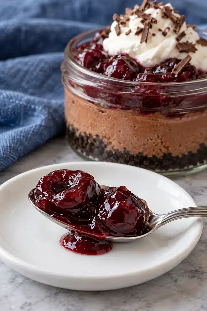 Thick cooled cherry sauce coating pitted cherries on a resting spoon without a watery puddle