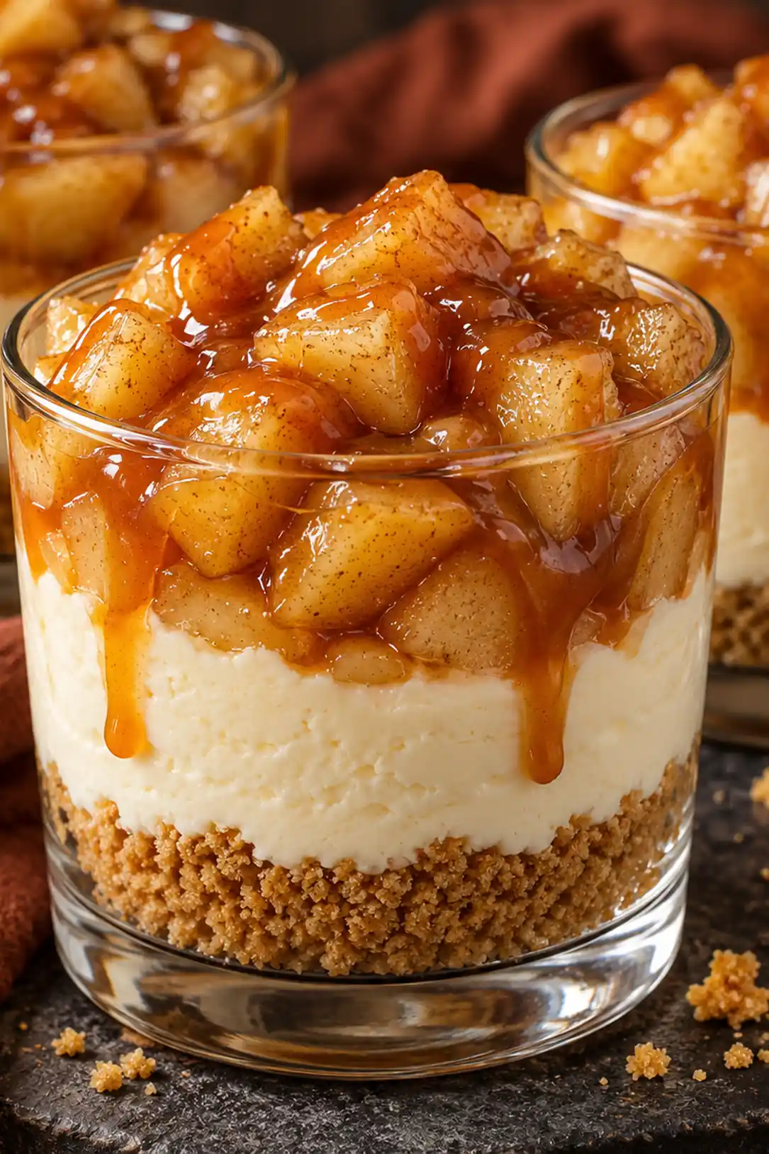 Caramel apple cheesecake cups with graham crumbs, creamy filling, cinnamon apples, and caramel
