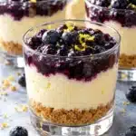 Lemon blueberry cheesecake cups with golden graham crumbs, ivory lemon filling and a distinct blueberry topping
