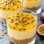Passion fruit cheesecake cups with vanilla crumbs, pale yellow filling and glossy golden seeded topping