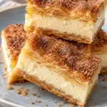 Sopapilla Cheesecake Bars with Cinnamon Sugar 10 Sopapilla cheesecake bars stacked to show golden crescent layers, creamy filling, and cinnamon sugar tops